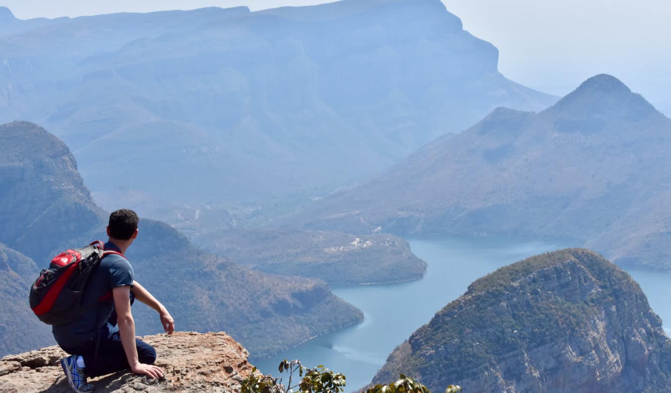 Nomadic Matt wearing a backpack overlooking a huge, lush canyon