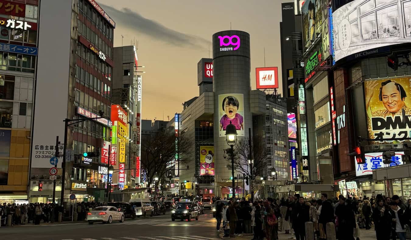 A busy intersection in Tokyo, Japan, with a lot of billboards lit up at night