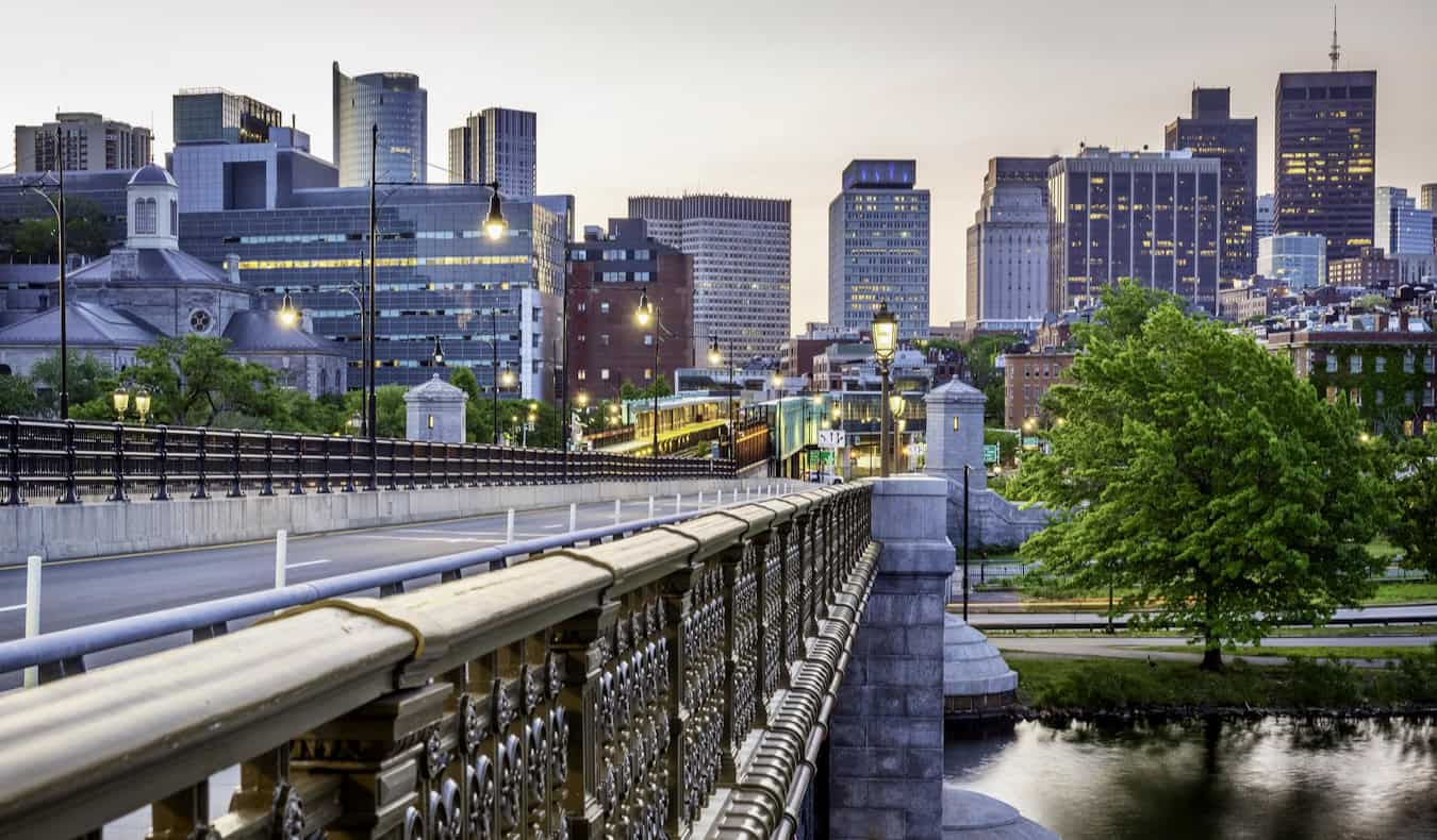 A view looking out at downtown Boston as seen from a bridge over the water at sunrise