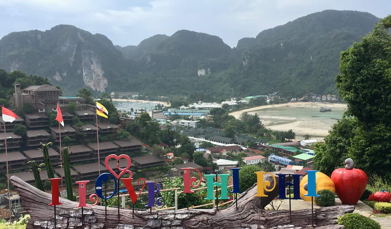 Uma placa dando boas-vindas aos visitantes em Ko Phi Phi, Tailândia, com colinas verdejantes ao fundo