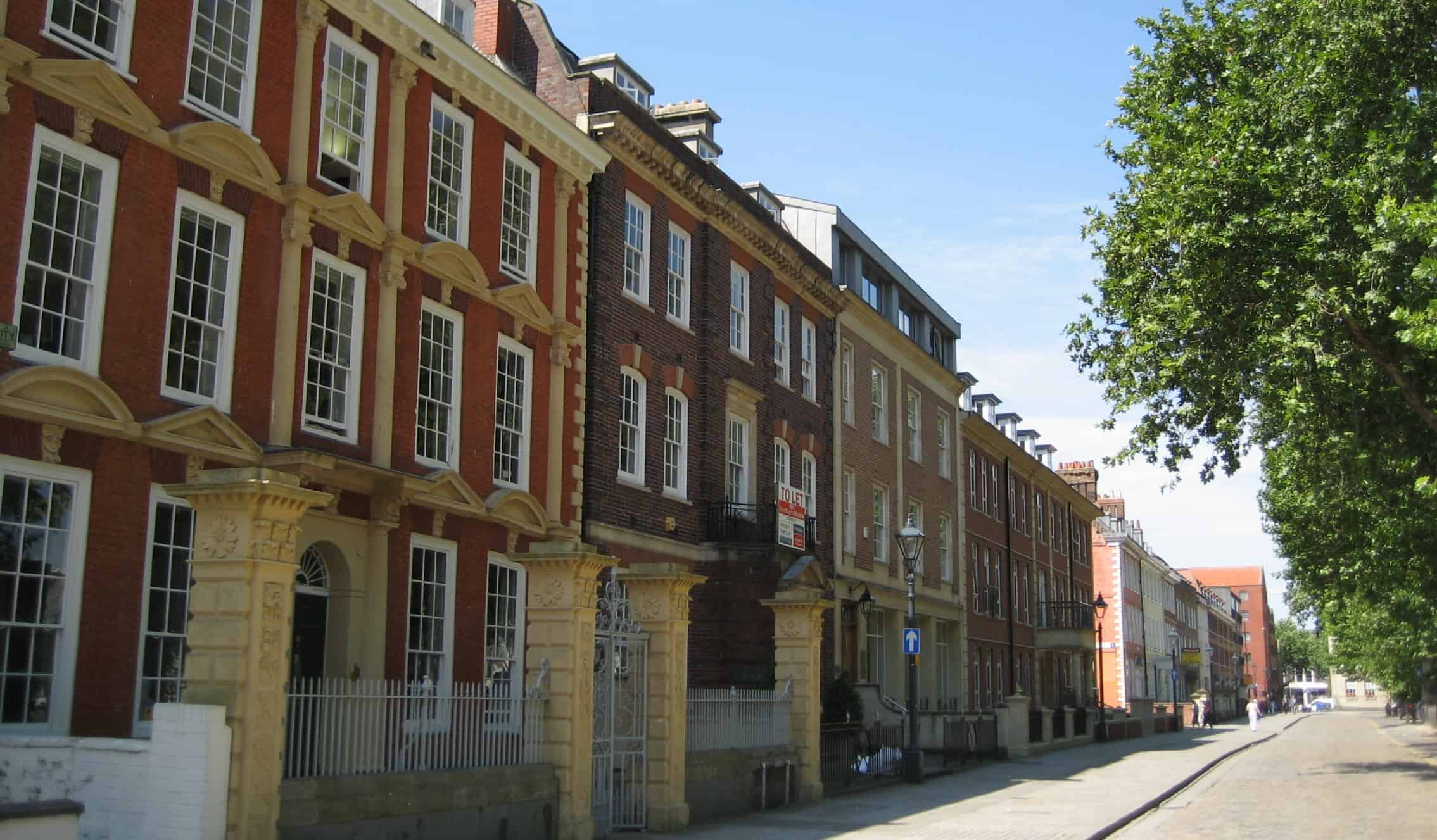 A row of historic brick townhouses on a cobblestone street in Bristol, UK