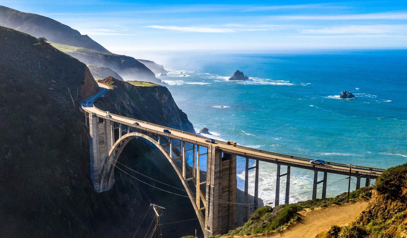 An arched bridge set against the rugged coasts and blue waters of Big Sur, California
