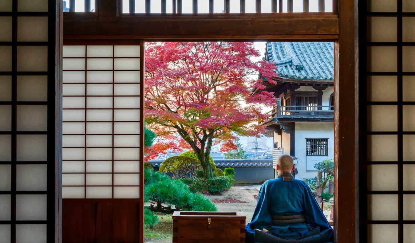 A long Buddhist monk sitting on the stoop of his temple in Japan