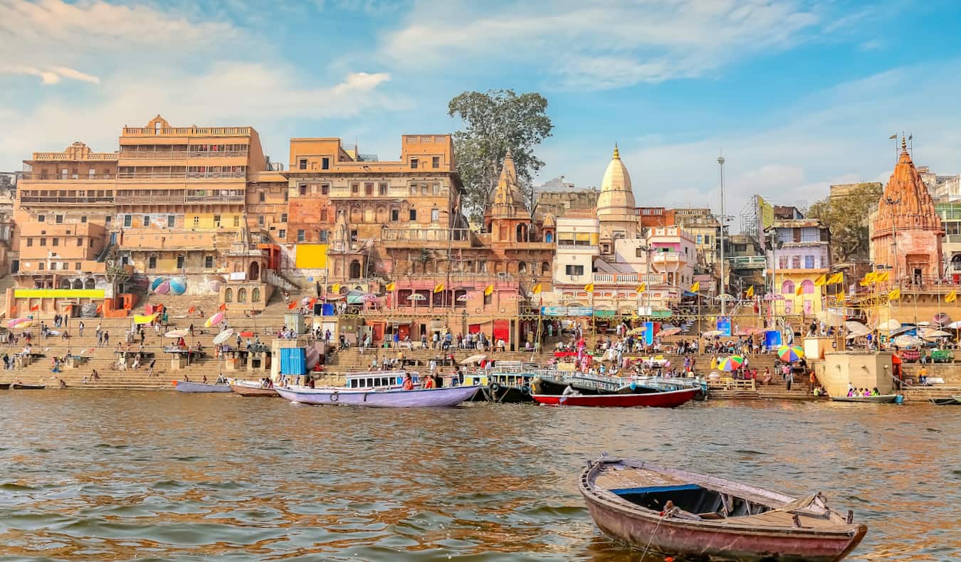 A view of old buildings along the famed Ganges River in India, with lots of people and boats