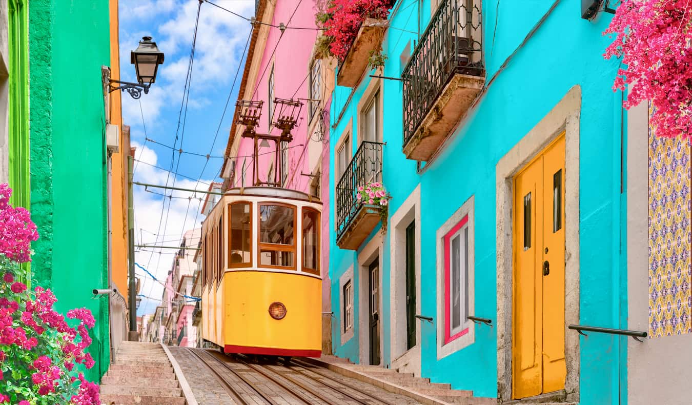 A narrow street with bright colors and an old tram going up the hill in Lisbon, Portugal