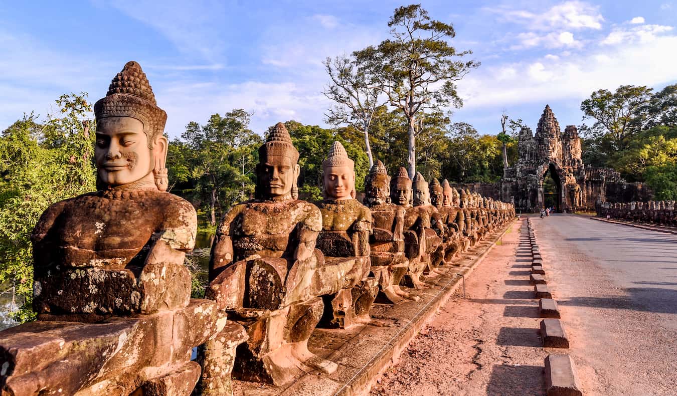 Old stone statues lining the ancient road in the ruins of beautiful Angkor Wat in Cambodia