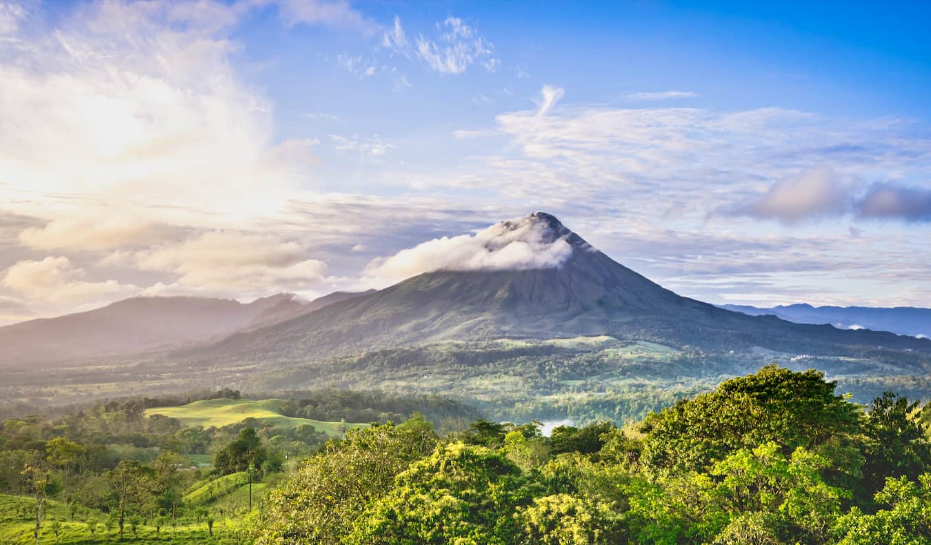 Une journée ensoleillée et lumineuse surplombant l'imposant volcan Arenal au Costa Rica, avec une jungle luxuriante dans toutes les directions.