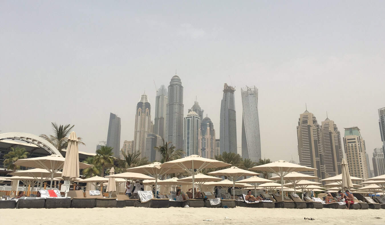 The towering skyline of downtown Dubai, as seen from the water with huge buildings in the background