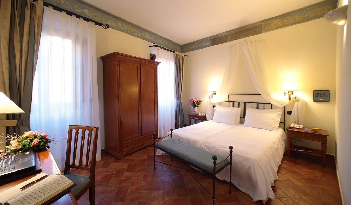 Hotel room with two twin beds side by side at Hotel Davanzati in Florence, Italy, desk, wooden wardrobe, terracotta tile floor and soft lighting