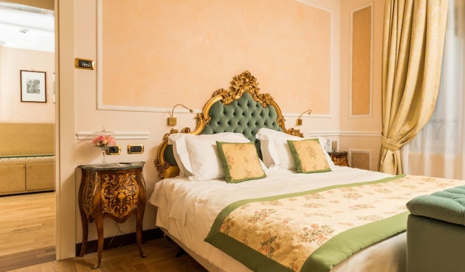 Luxurious bed with golden headboard at the 5-star Hotel Bernini Palace in Florence, Italy