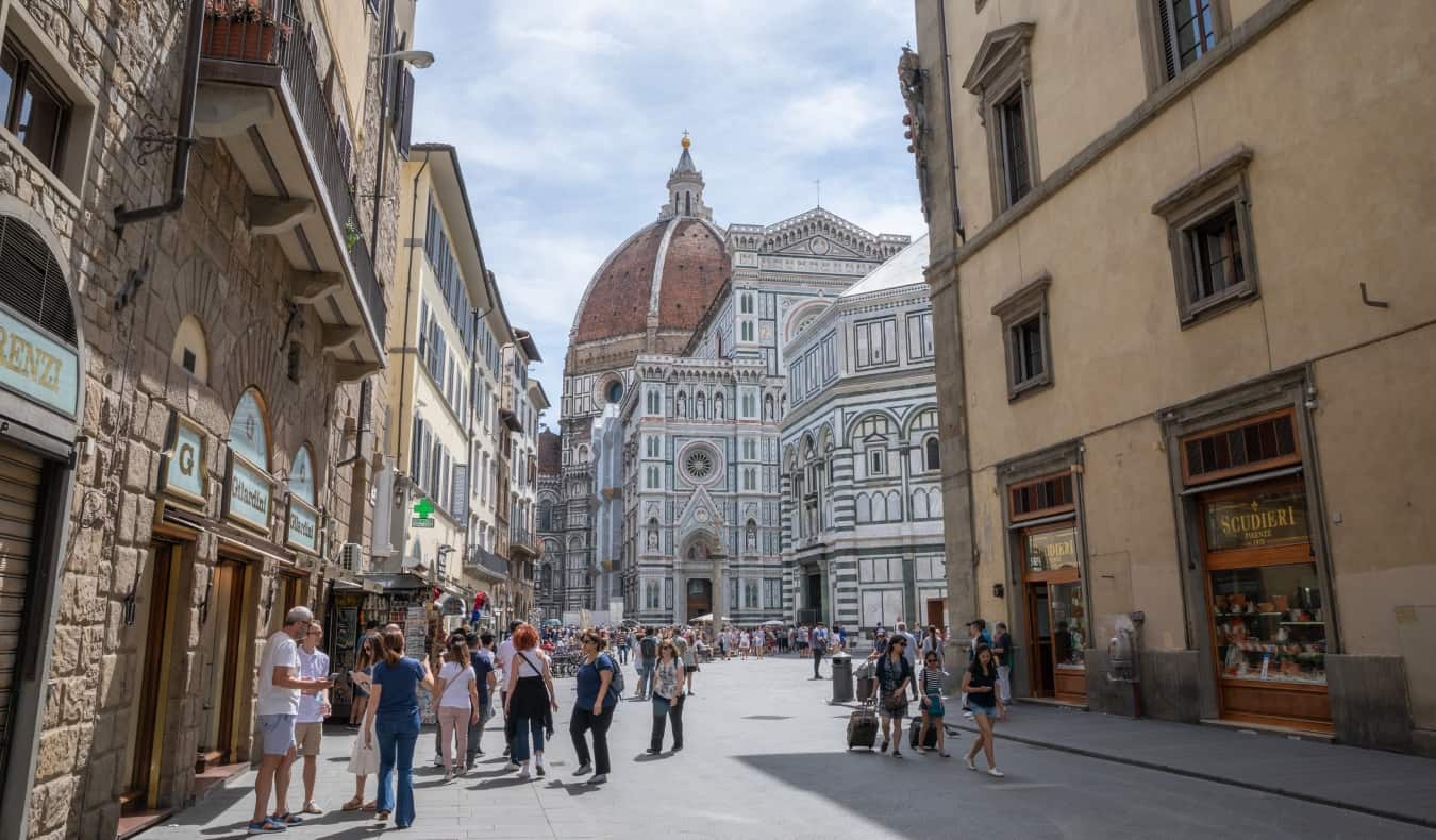 People milling about in the street with the iconic Duomo cathedral in the background in Florence, Italy