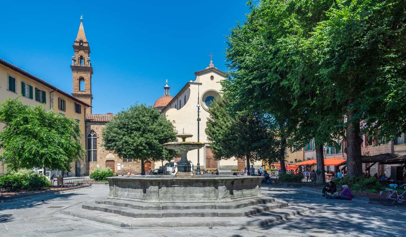 People sitting around near a fountain in the leafy Santo Spirito piazza in the Oltrarno area of Florence, Italy