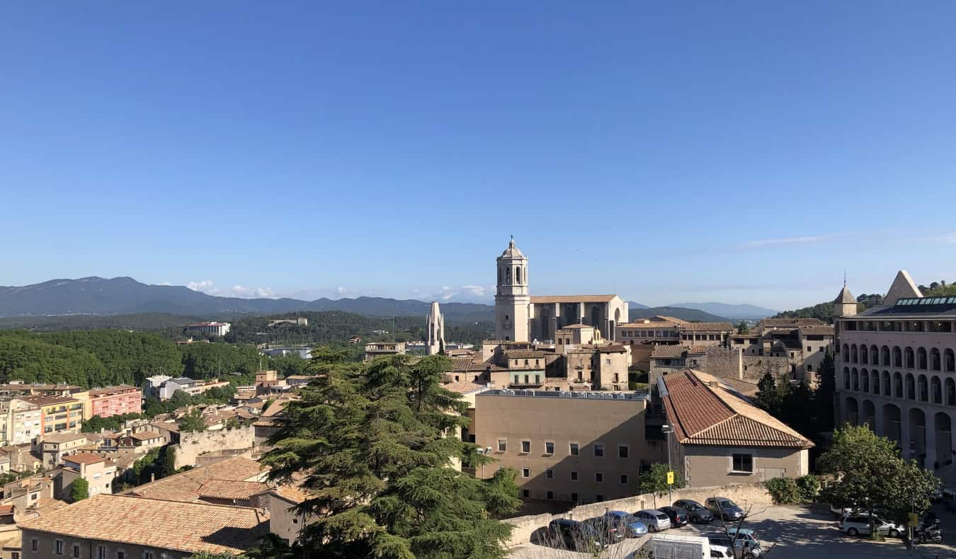 View over the terracotta roofs, with a cathedral and mountains in the background, in Girona, Spain