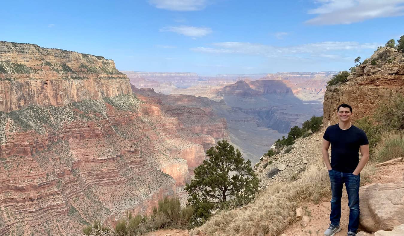 Nomadic Matt posing for a photo near the ridge of the stunning and massive Grand Canyon in the USA