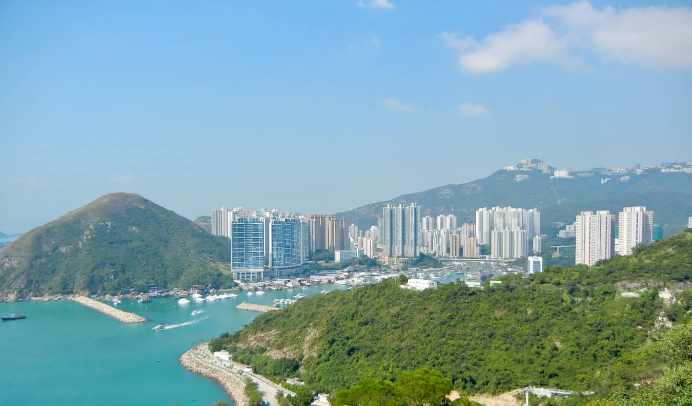 A sunny day overlooking the sprawling city of Hong Kong, with lush greenery in the background