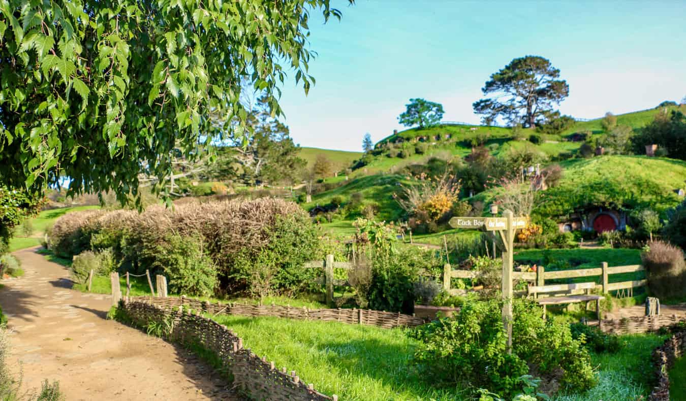 The lush, rolling hills of Hobbiton, in sunny New Zealand, featuring hobbit holes and signposts