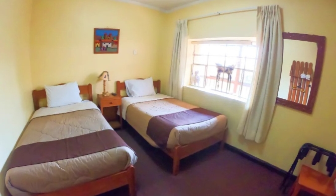 Single beds in a simple yellow room at Hospedaje Turístico Recoleta, a hostel in Cusco, Peru