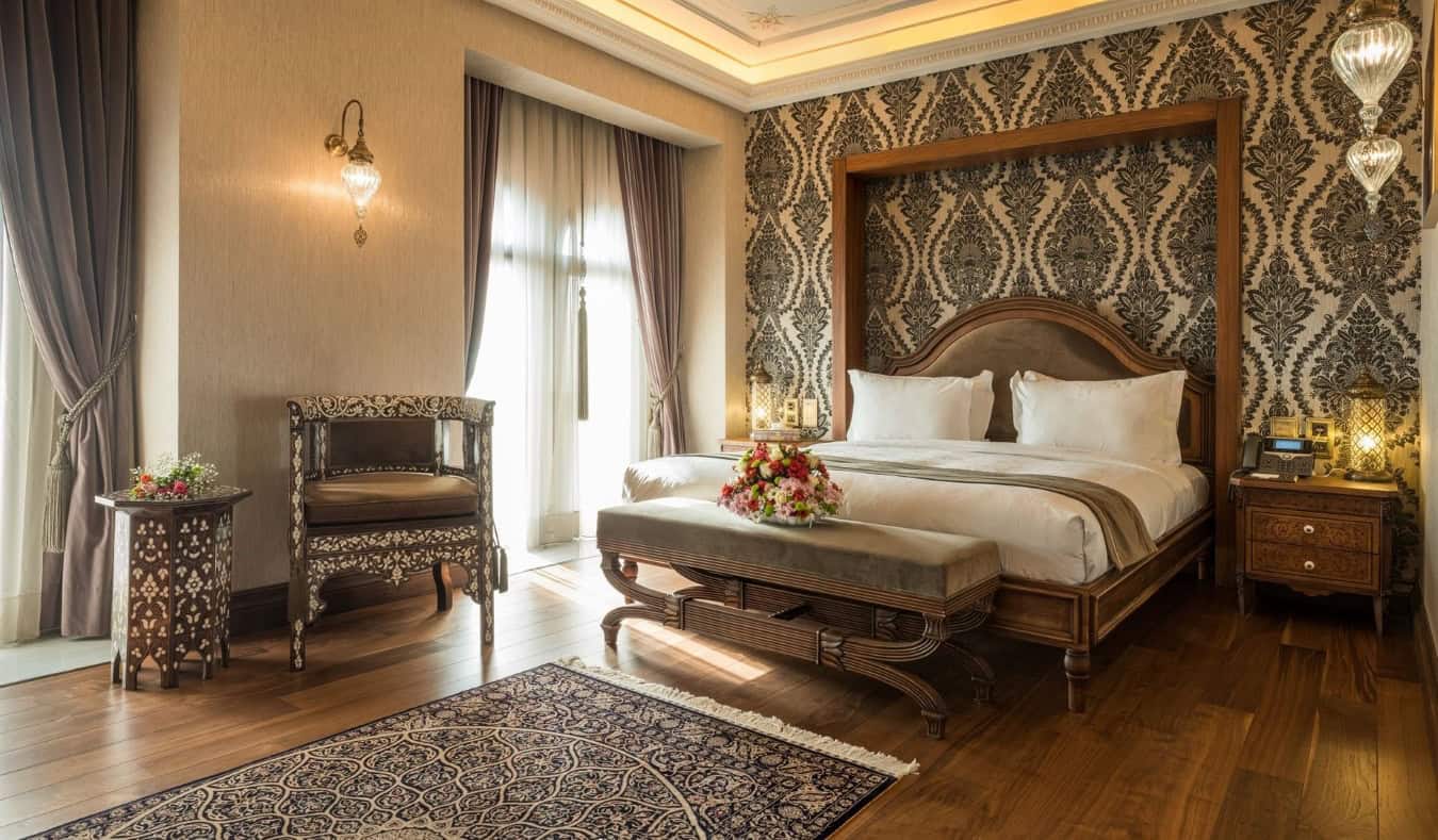 Large guest room with a king bed, hardwood floors, and tapestries on the walls at AJWA Sultanahmet, a five-star hotel in Istanbul, Turkey