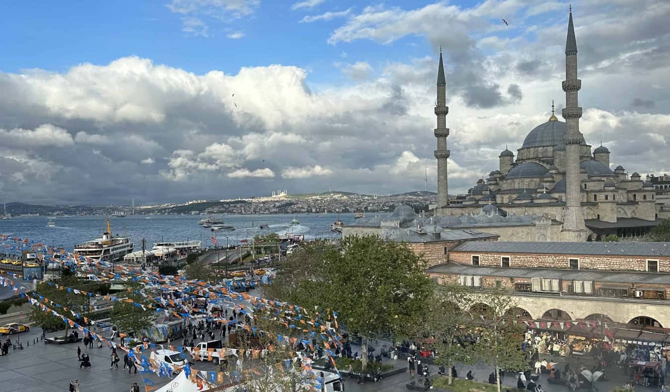 horizonte de Istambul, Turquia, com uma grande mesquita ao fundo e pessoas circulando à beira-mar em primeiro plano