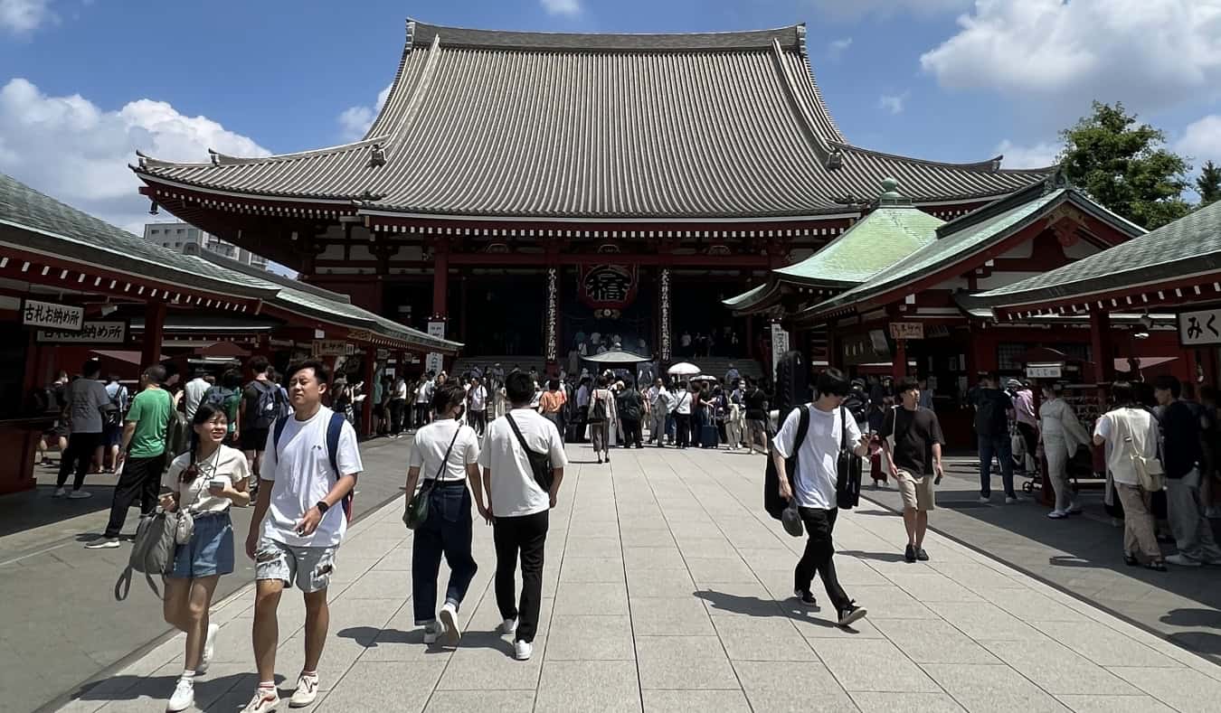 People walking around in front of a temple in Tokyo, Japan