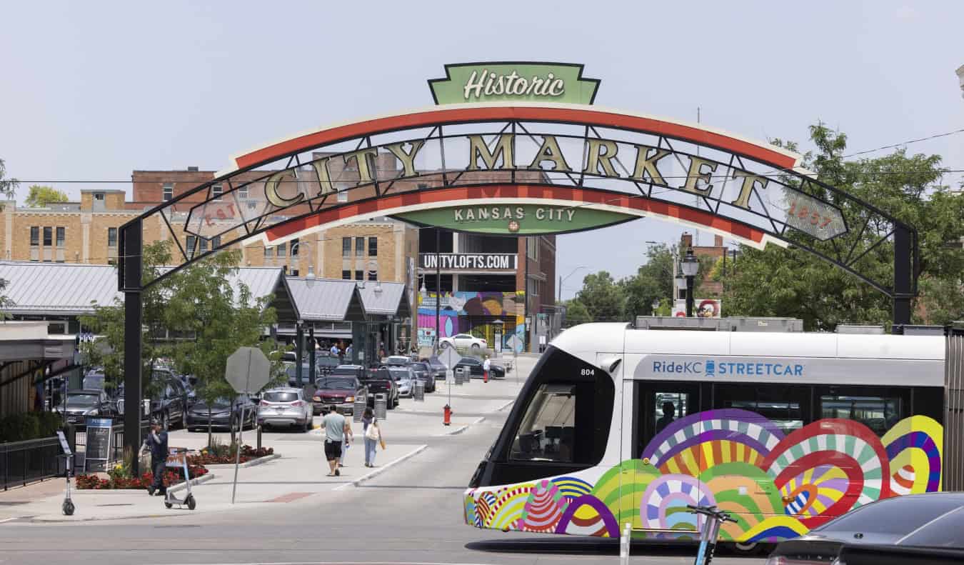 A colorful streetcar passes in front of a historic market in Kansas City