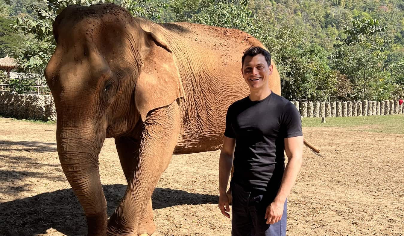 Nomadic Matt standing in front of an elephant at an elephant sanctuary in Thailand