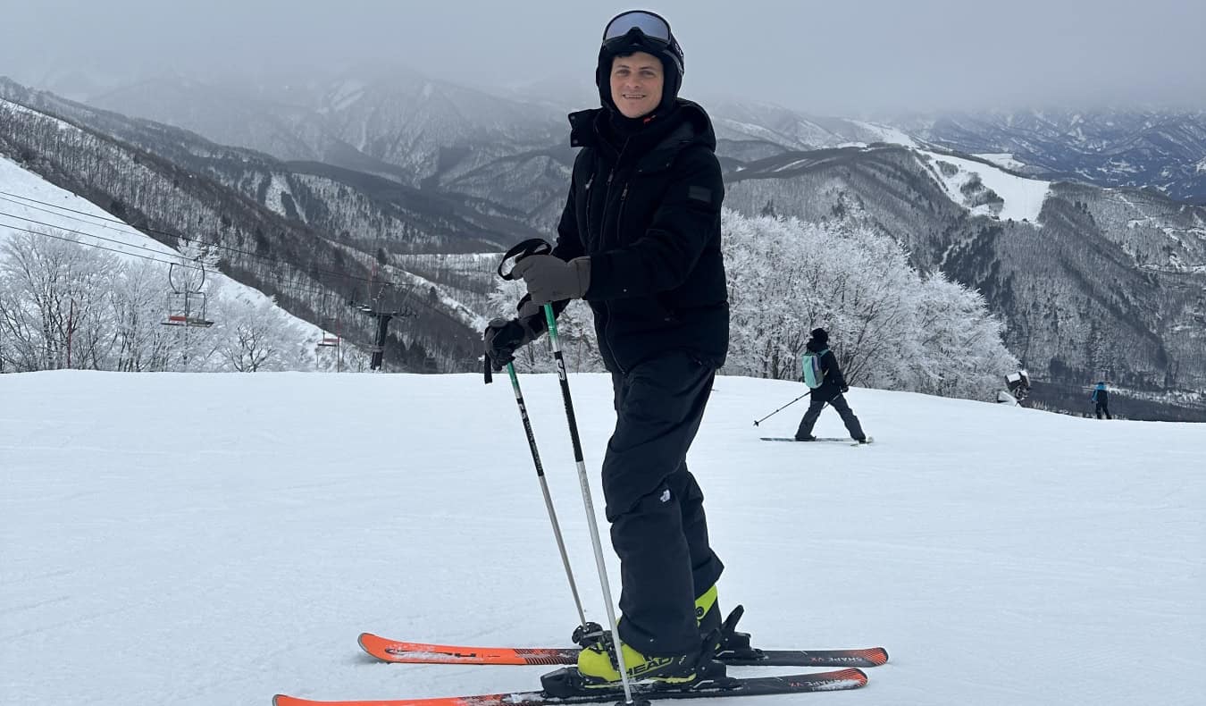 Nomadic Matt standing on skis on a snowy mountain in Japan