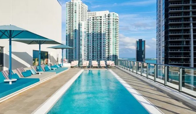 Pishinë e gjatë drejtkëndore në çati me shezllone buzë pishinës, e rrethuar nga rrokaqiejt e Miami, Florida në hotelin qytetarM Miami Brickell