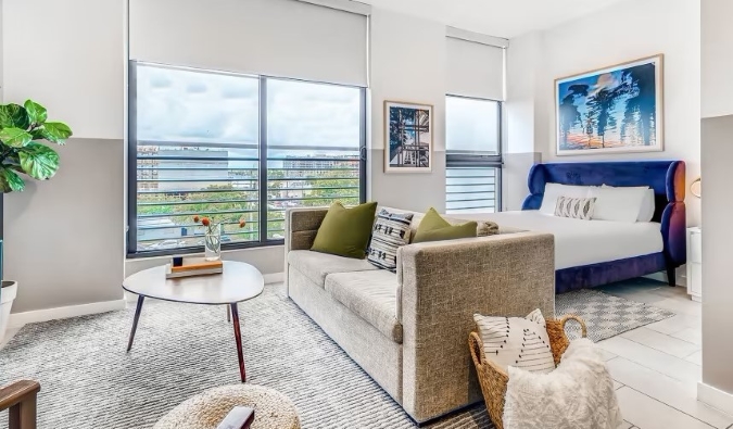 Shtrat dhe divan në një apartament me dritare nga dyshemeja deri në tavan në hotelin e apartamenteve Sentral Wynwood në Wynwood, Miami 