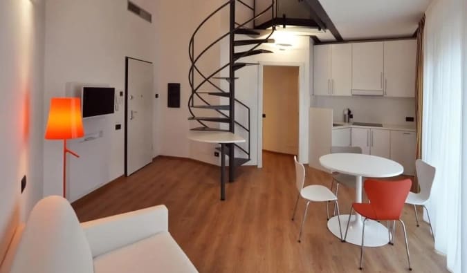 The kitchen area and living room area with a spiral staircase leading up to a loft at BB Hotels Aparthotel Isola in Milan, Italy