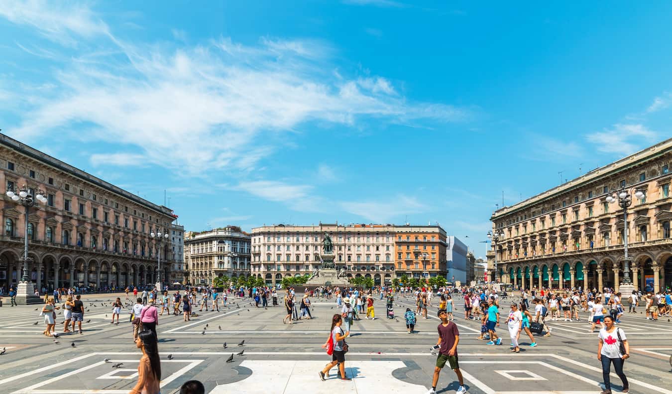 People strolling around a massive open plaza in the Centro Storico district of sunny Milan, Italy