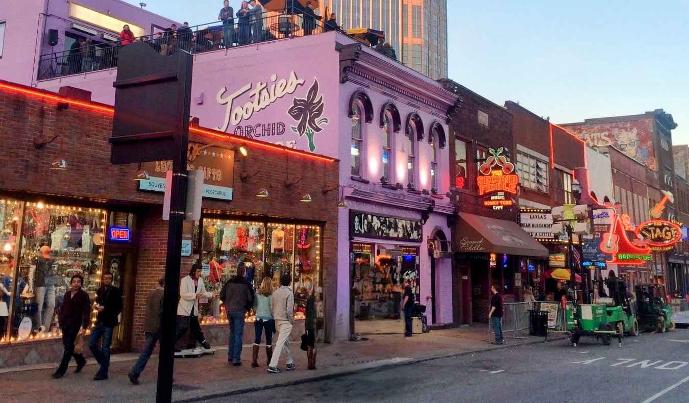 Le bâtiment couleur lavande du Tootsie's Orchid Lounge au premier plan sur Broadway historique dans le centre-ville de Nashville, éclairé la nuit