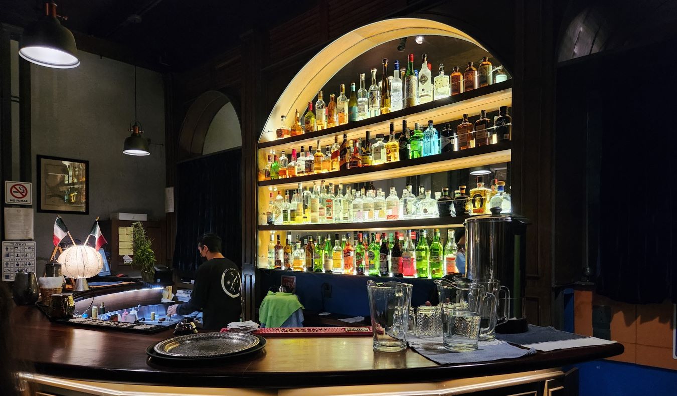 A bar in Oaxaca, Mexico, with a curved archway filled with liquor bottles behind it