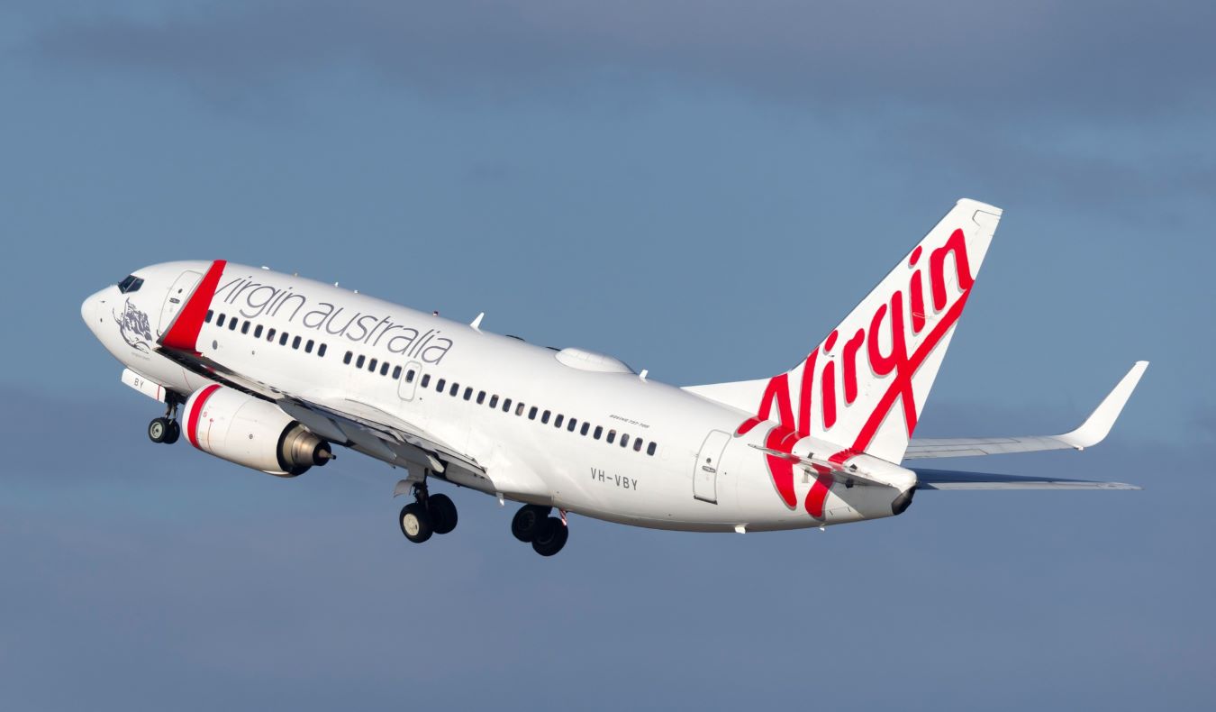 A Virgin Australia airplane flying against a bright blue sky