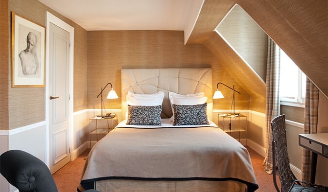 Një dhomë komode hoteli me një krevat mbretëreshë, ndriçim të butë, një pikturë në mure dhe ngjyra pastel në të gjithë Parisin, Francë