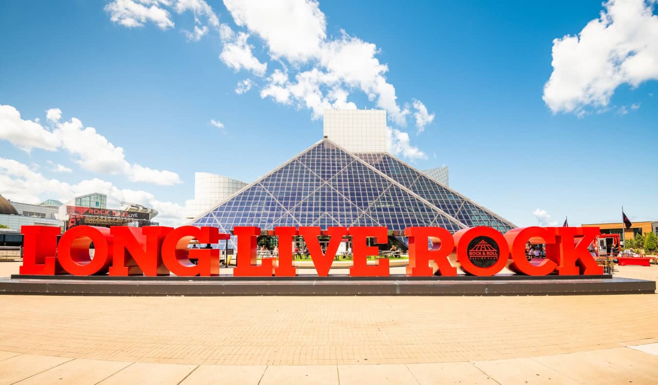 Giant red letters that say 'long live rock' in front of the huge glass pyramid of the Rock and Roll Hall of Fame in Cleveland, Ohio