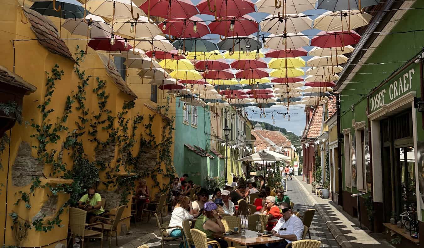 Colorful umbrellas hung over restaurant tables in a street in Romania