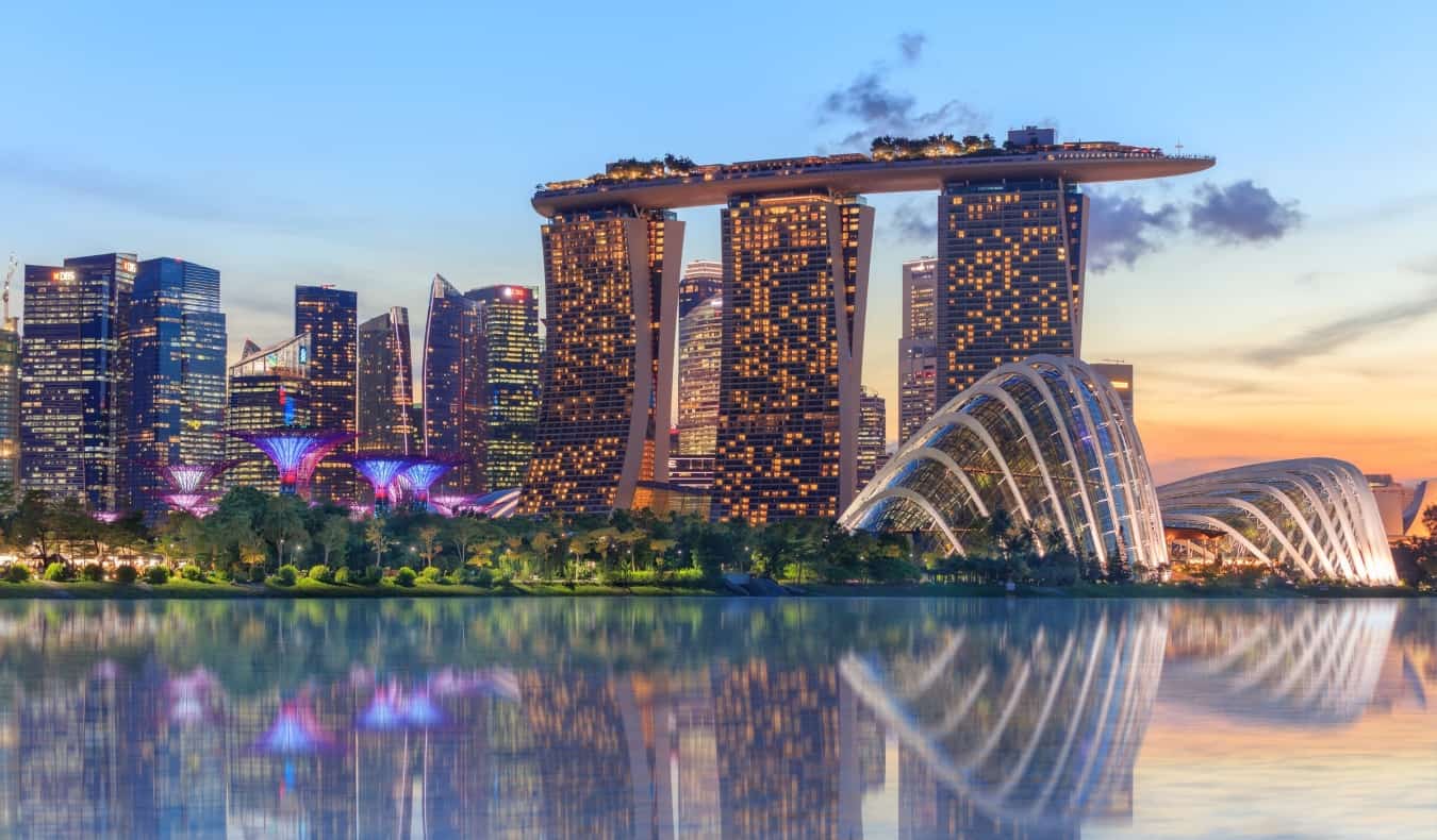 Korija e superpemëve të Singaporit, sera e kopshtit me re dhe hoteli Marina Bay Sands duke reflektuar në ujë në muzg me drita të ndezura