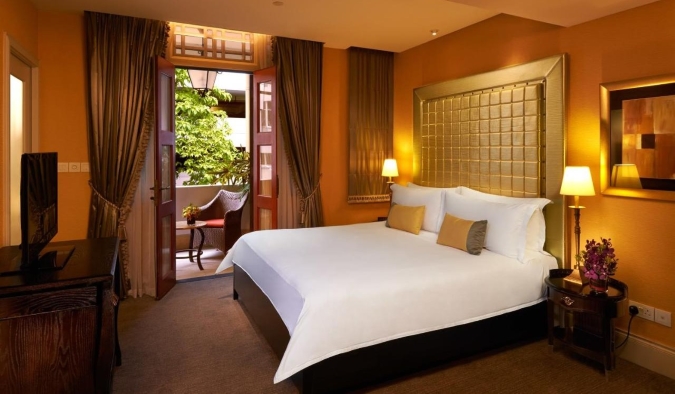 Një dhomë hoteli e dekoruar me guxim me mure portokalli dhe një ballinë të madhe ari në hotelin The Scarlet në Singapor