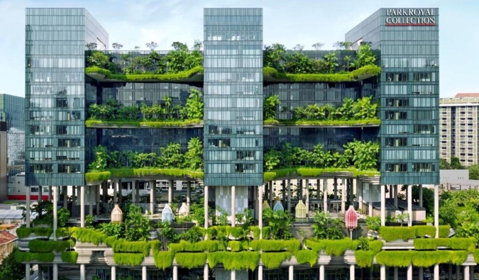 Pamja e jashtme e PARKROYAL COLLECTION Pickering, një hotel me 5 yje në Singapor, i mbuluar me bimë të harlisura që rrjedhin nga ballkonet