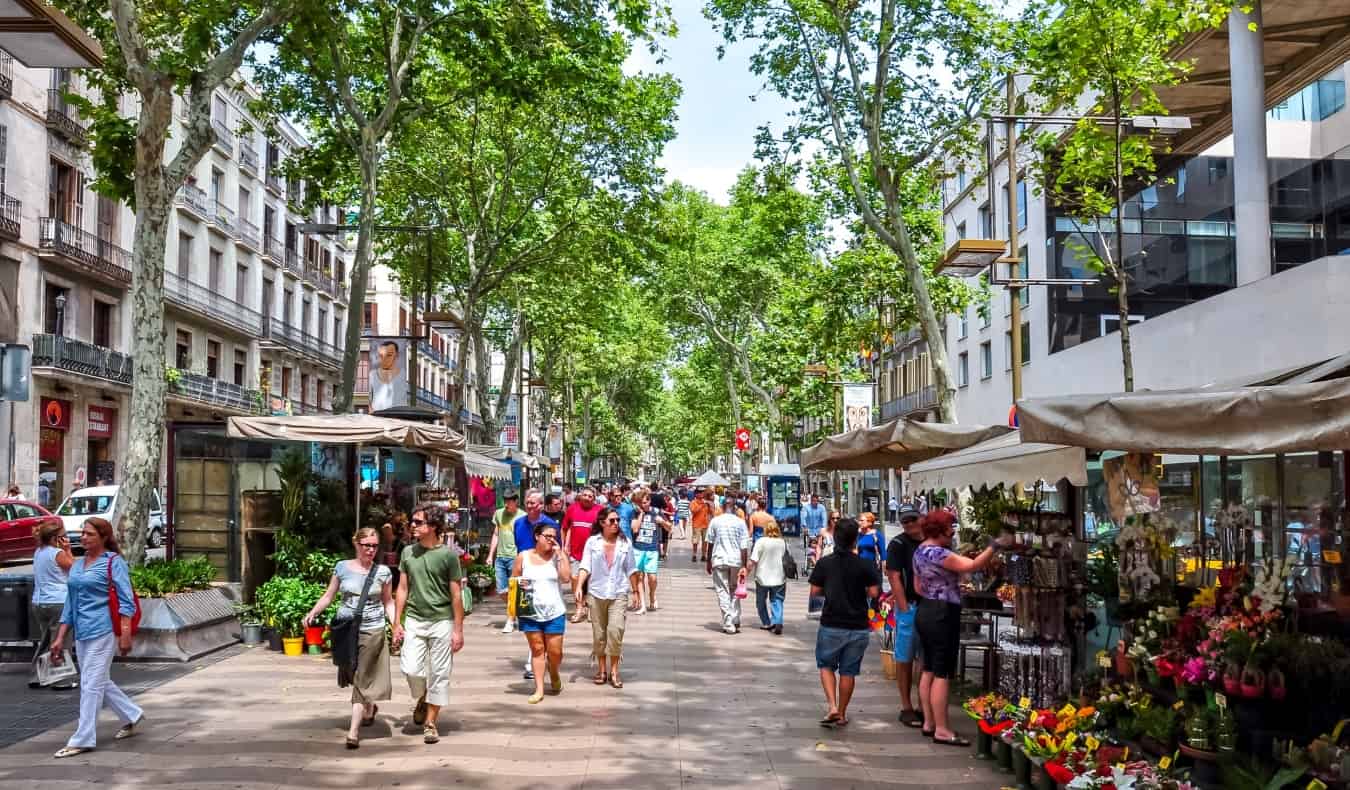 People walking down the famous pedestrianized street of La Rambla, with stalls lining both sides in Barcelona, Spain