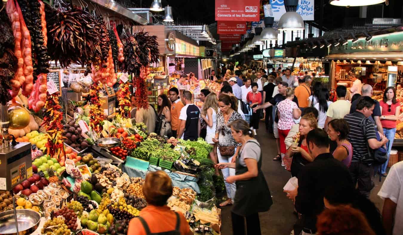 Crowds of people walking around the bustling Boquería market in Barcelona, Spain