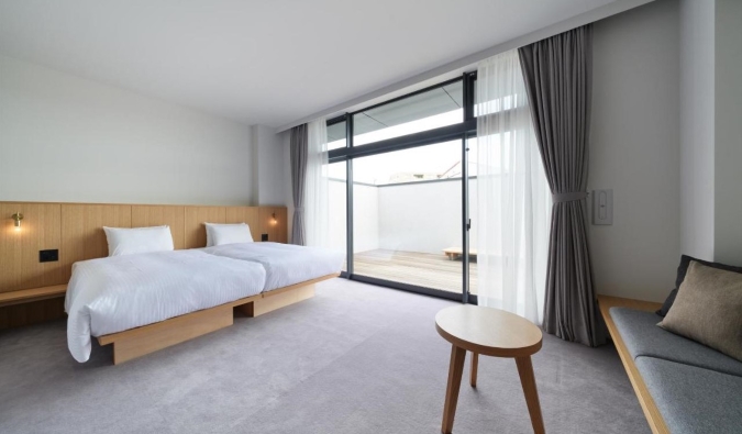 A minimal hotel room with just a double bed and large floor-to-ceiling windows in Tokyo, Japan
