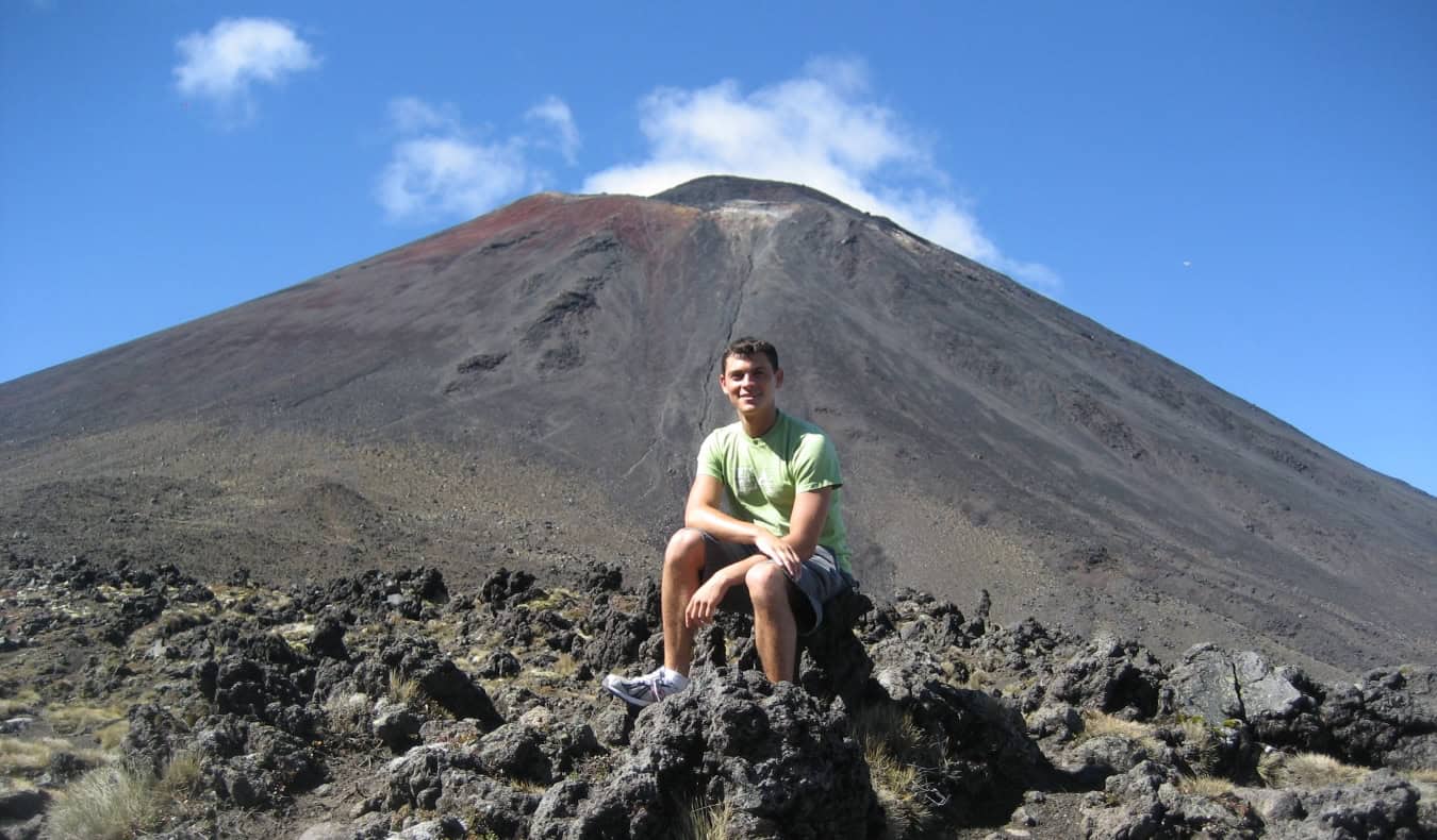 Blogger Nomadic Matt sitting in front of Mount Ngauruhoe, a volcanic cone in Tongariro National Park, New Zealand