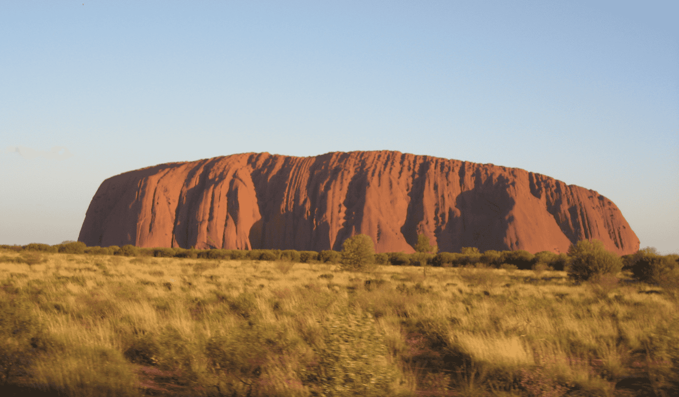 The giant orange Uluru rock surrounded by desert in Australia