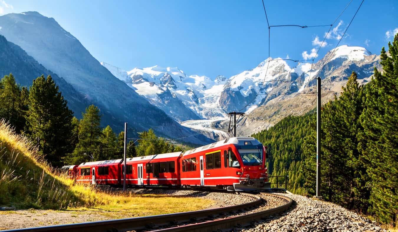 A Eurail train traveling through the mountains on a sunny summer day
