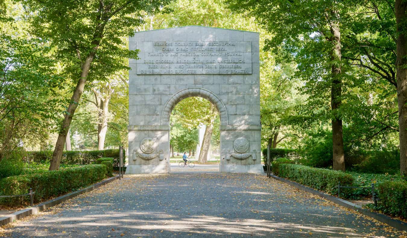 A view of the Soviet Arch with a woman cycling in Treptower Park in Berlin, Germany