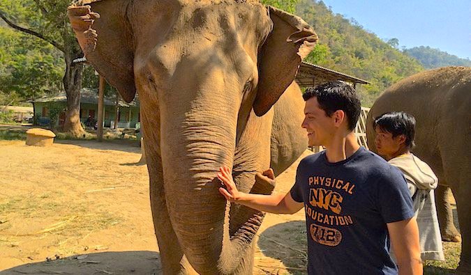 Nomadic Matt Kepnes playing with a Thai elephant at the Elephant Nature Park