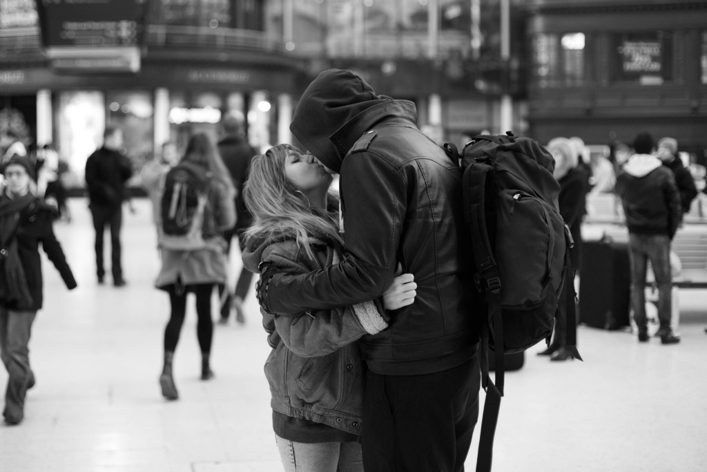 loving black and white photo of backpackers kissing at the transportation hub while traveling