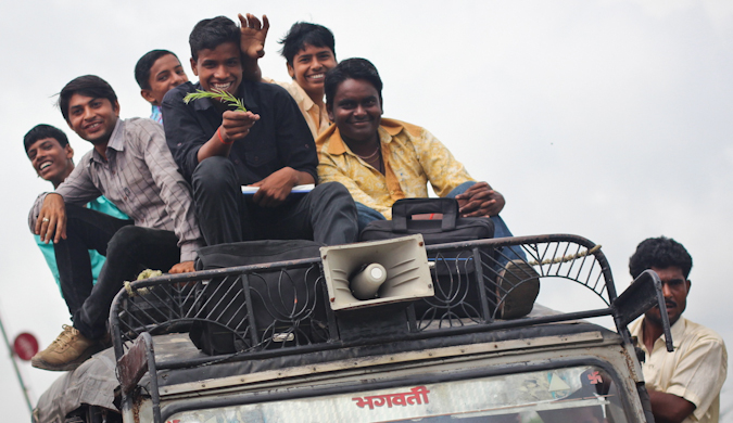 A group on locals on the top of a car as it moves